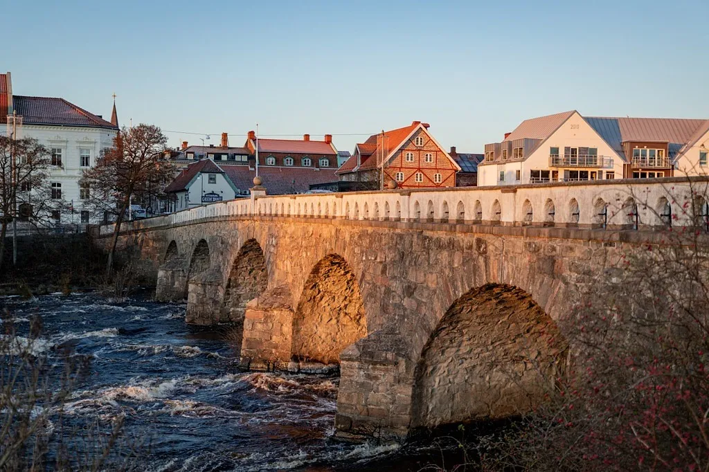 Vacker stenbro i morgonljus med staden i bakgrunden