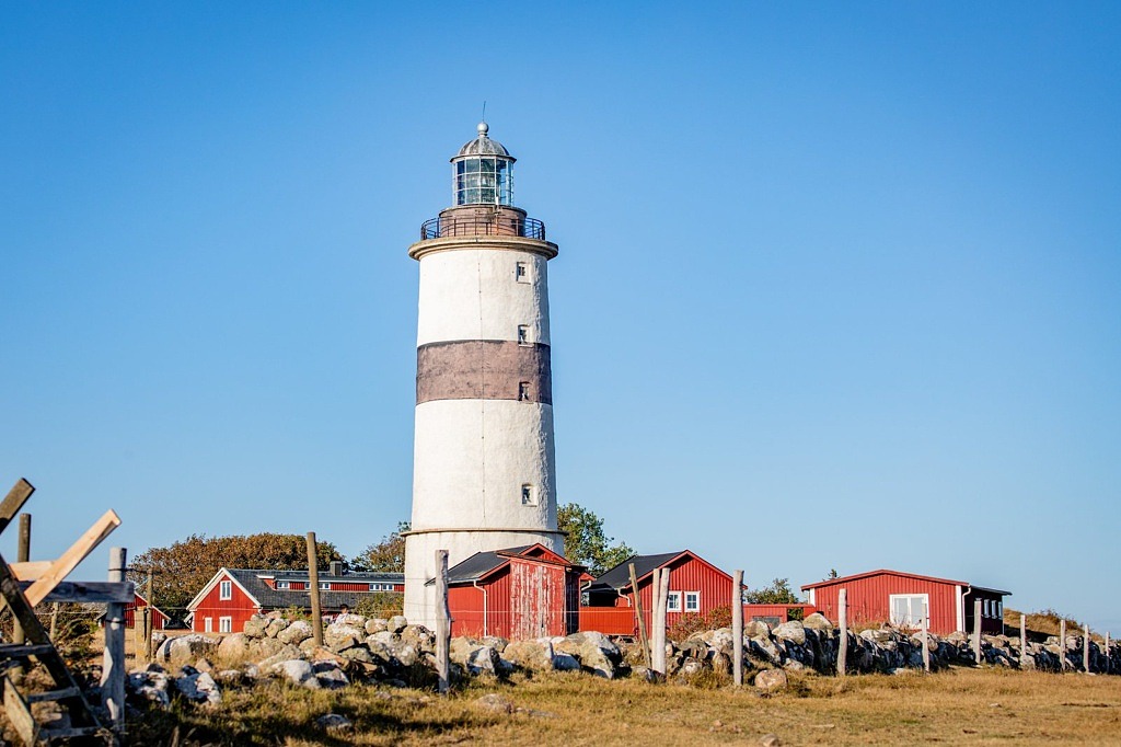 fyr står band röda fiskebodar