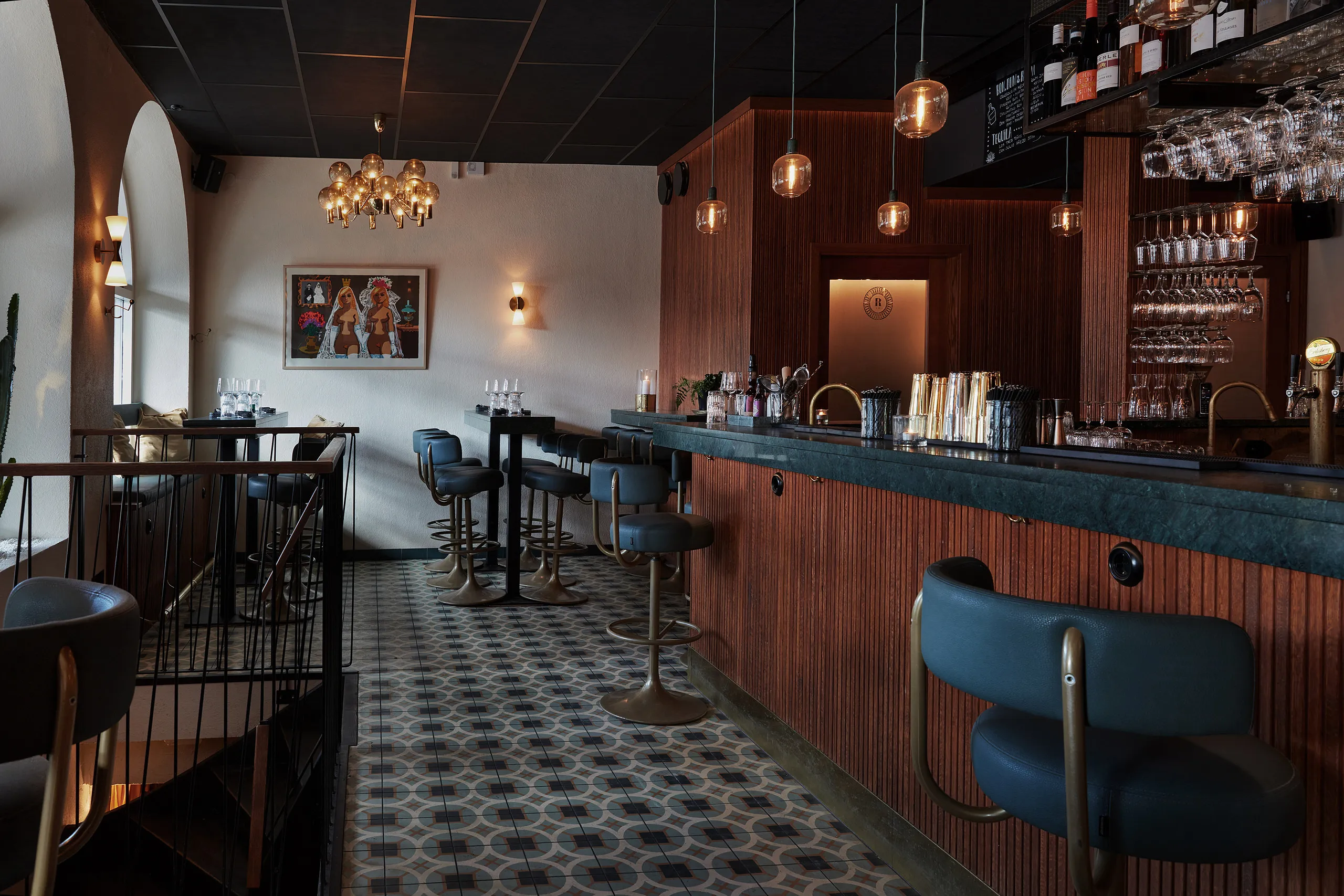 Restaurangmiljö i mörkt trä med görna barstolar.