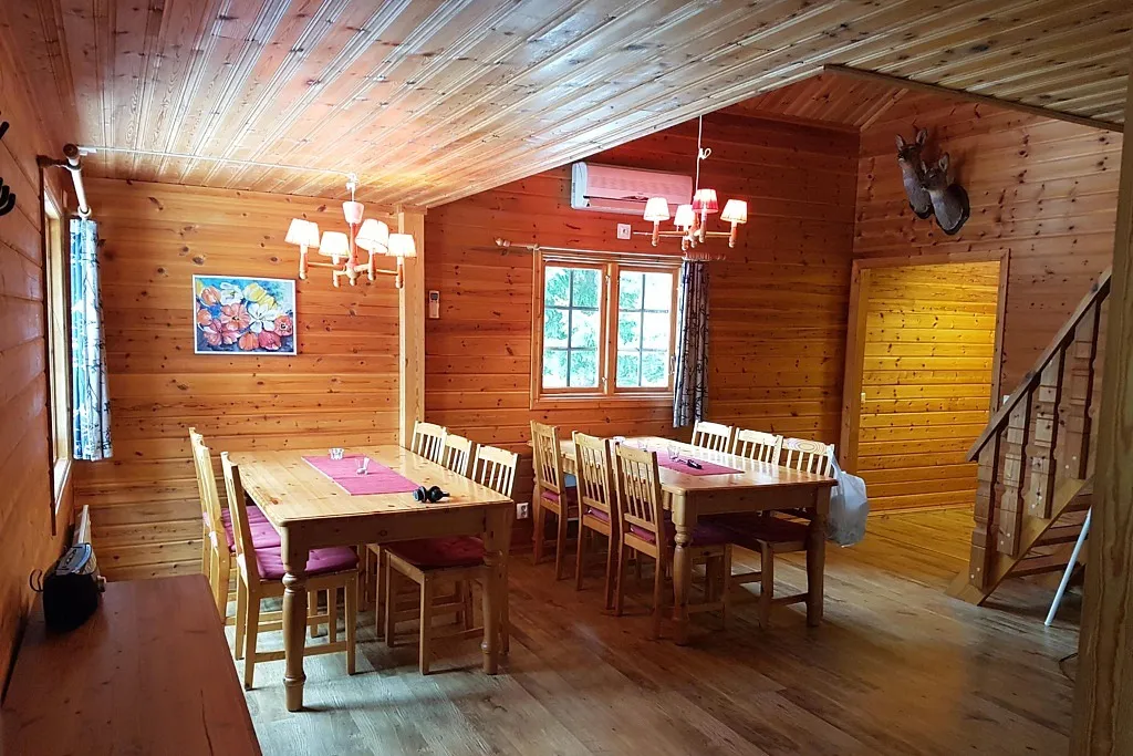 Matsal med liggande träpanel med med två matbord.