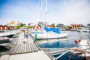 person går på brygga bland segelbåtar.