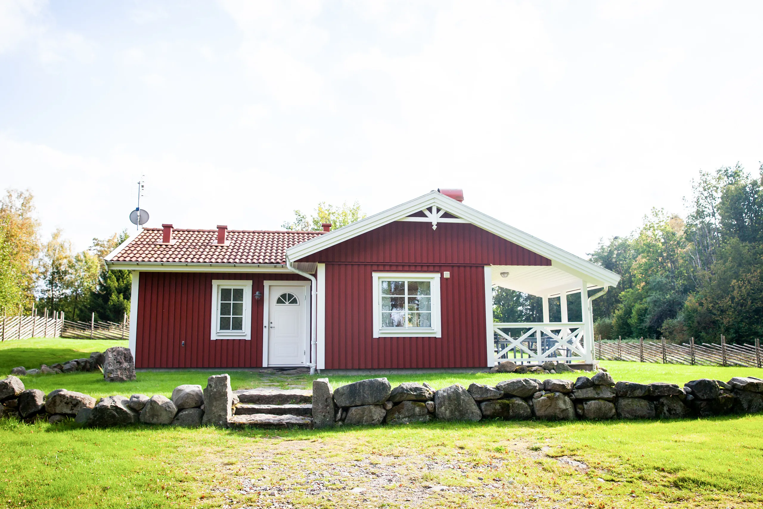 En röd stuga omgiven av grönska.