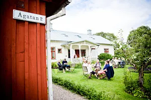 Trädgårdscafé med vitt hus i bakgrunden.