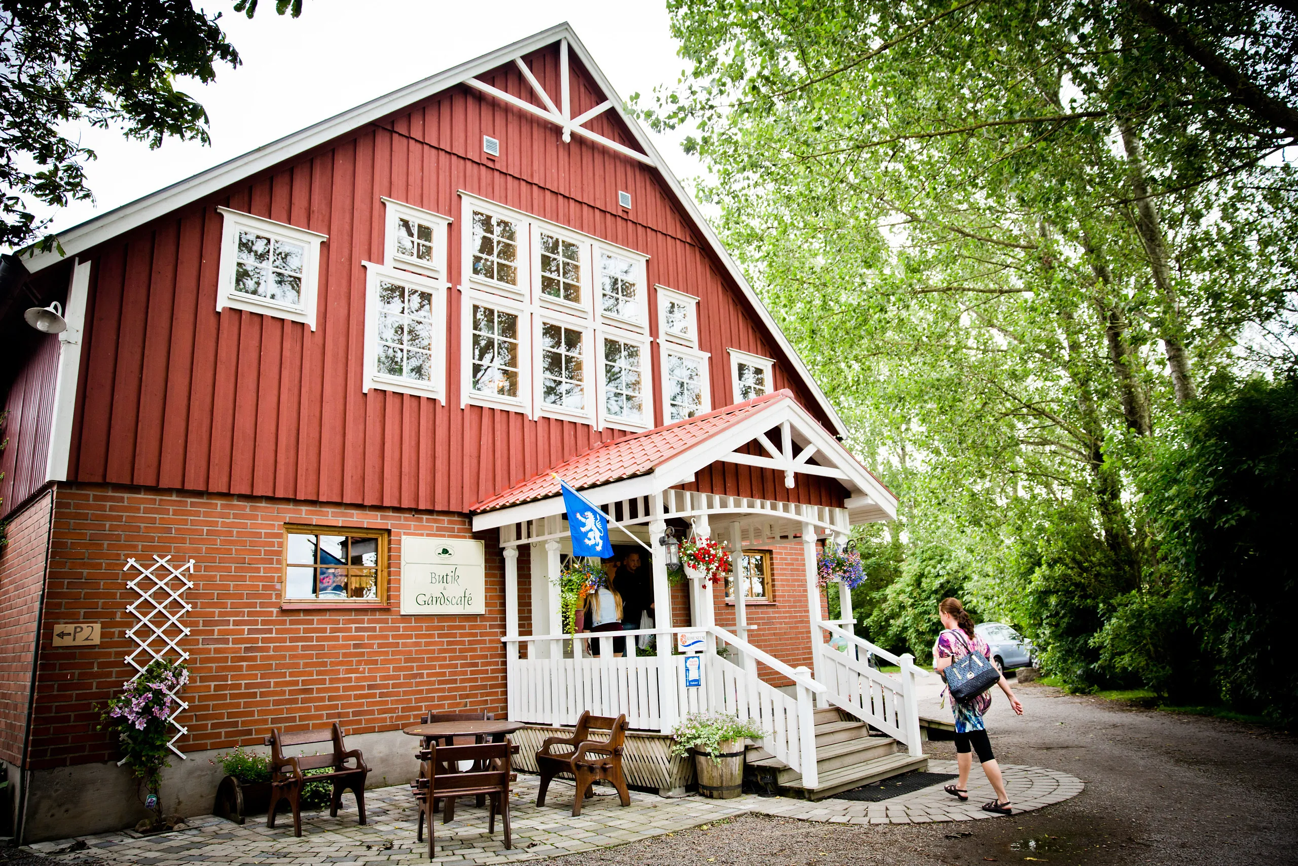 Fasad på stort rött hus, en kvinna är på väg in.