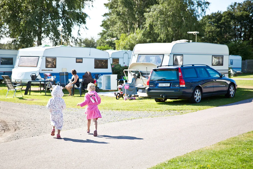 Två barn springer bland husvagnar på en camping.