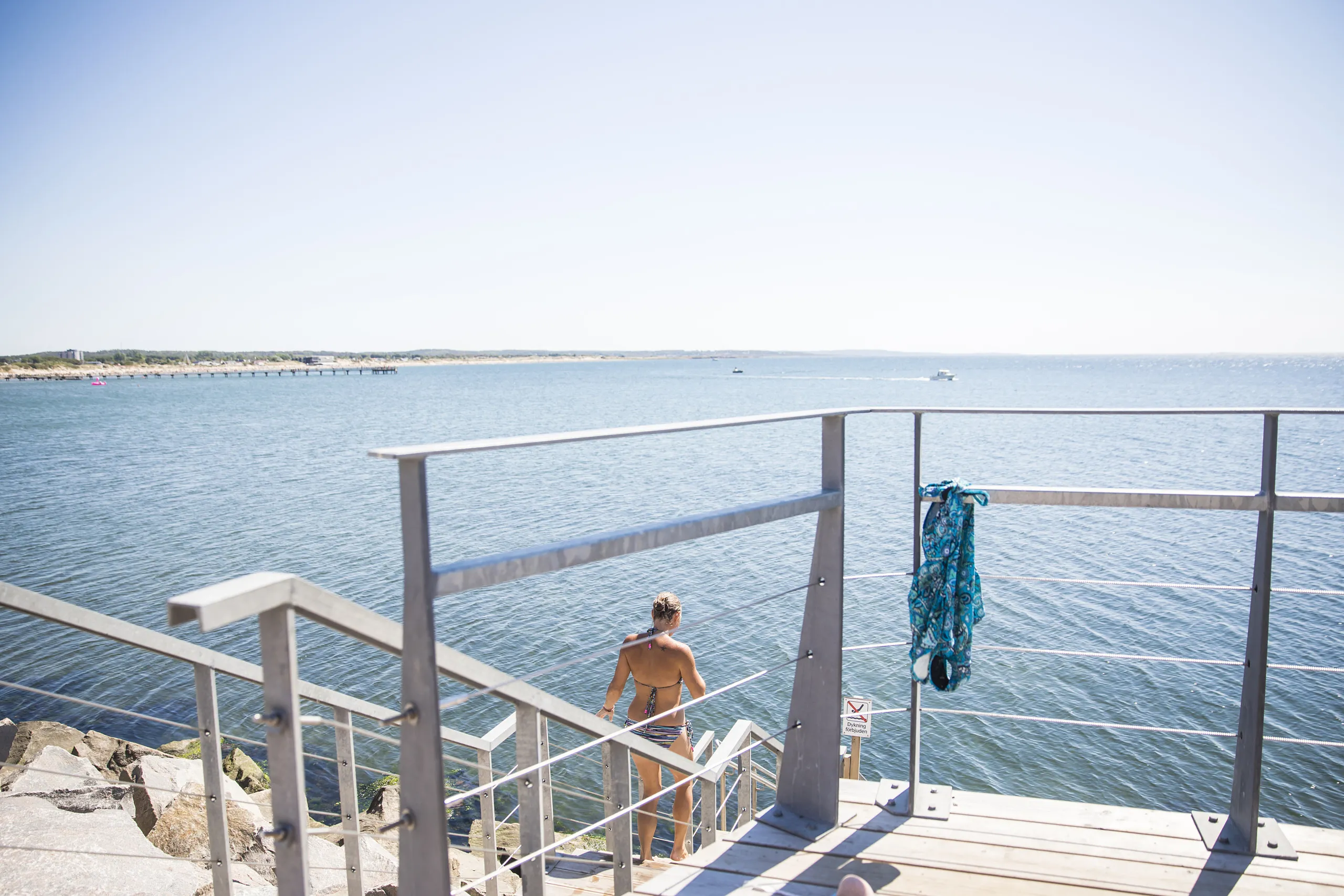 Kvinna går i vattnet från bryggan