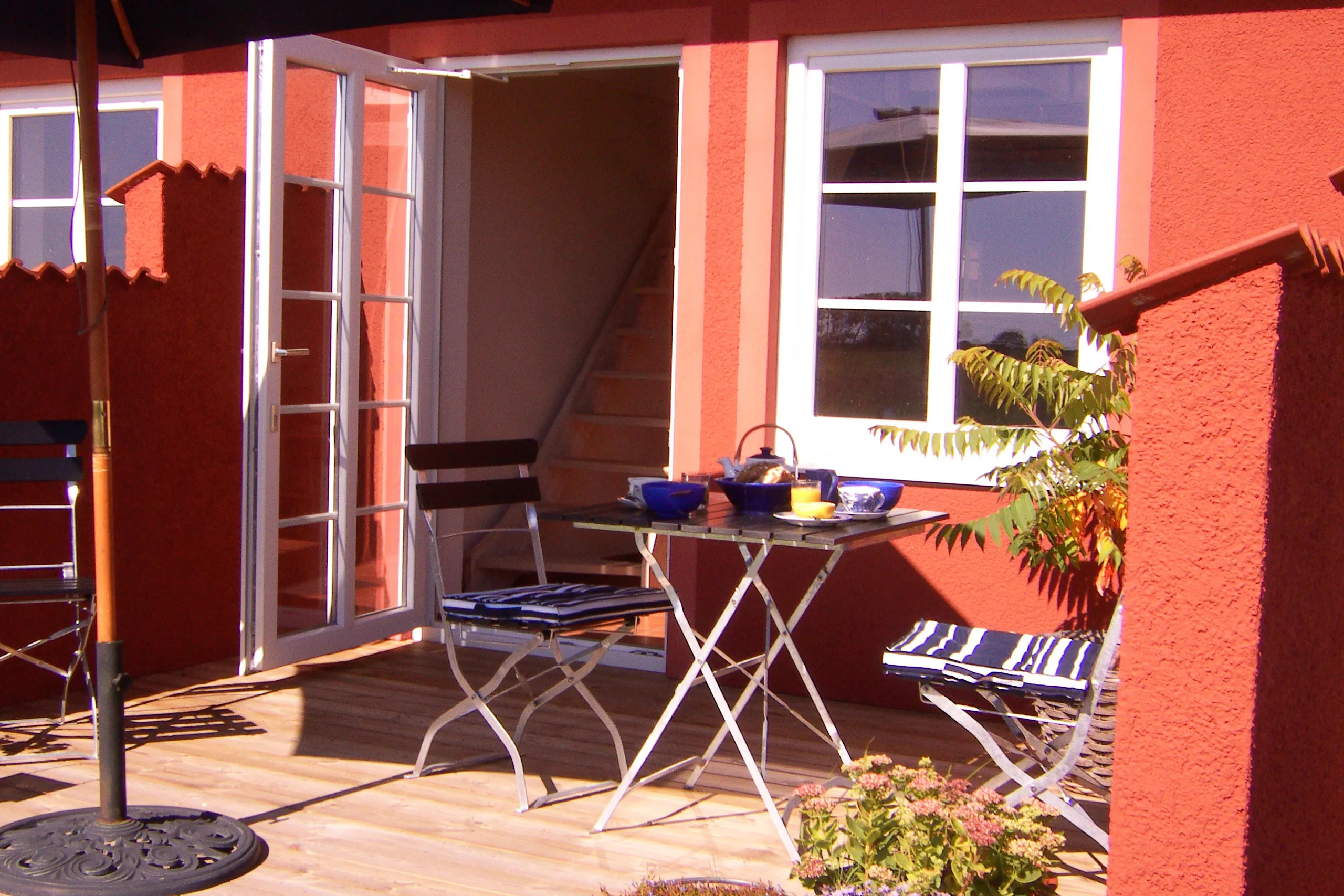 En liten uteplats med caféset mot röd fasad.