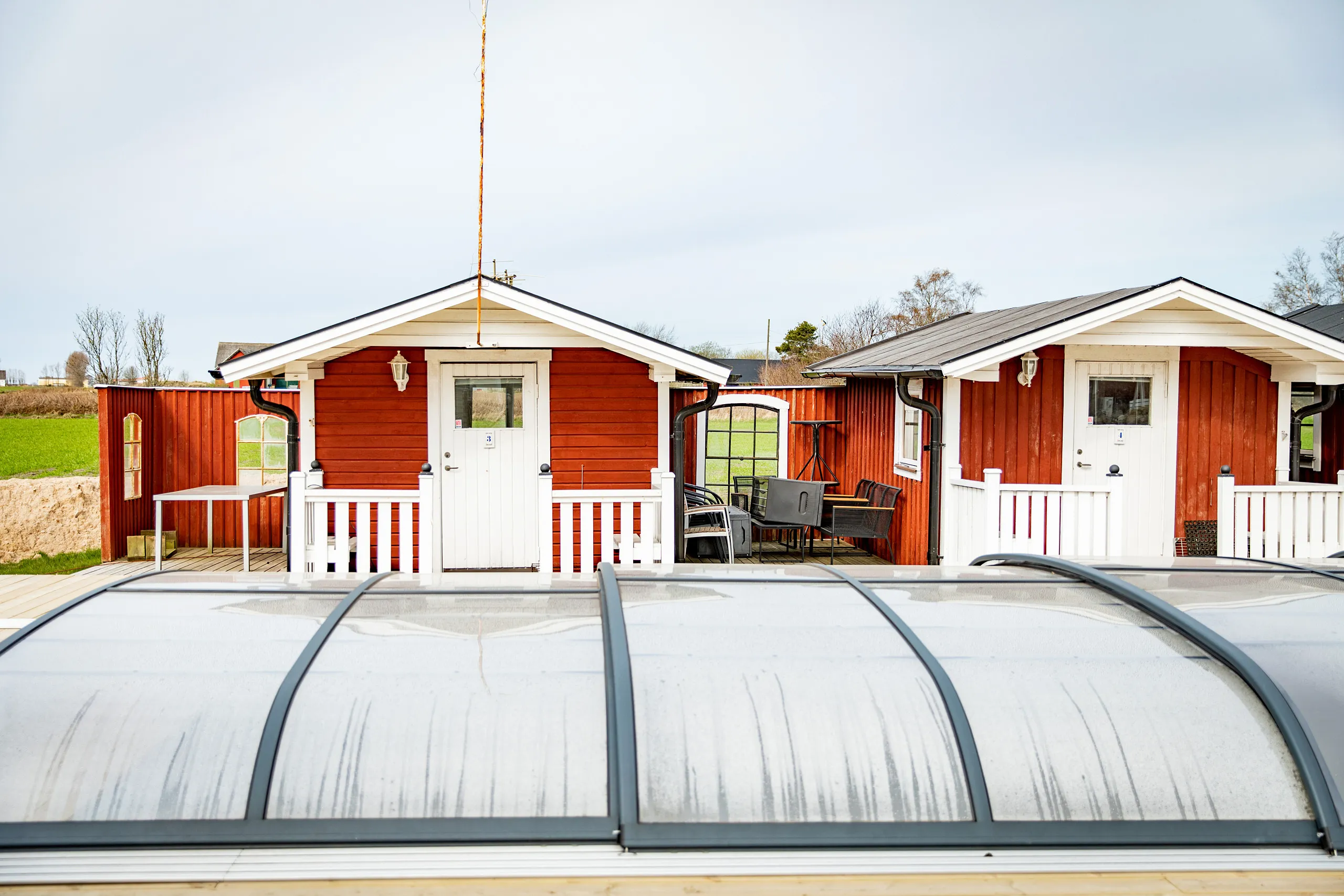 Röda små stugor framför en pool med pooltak.