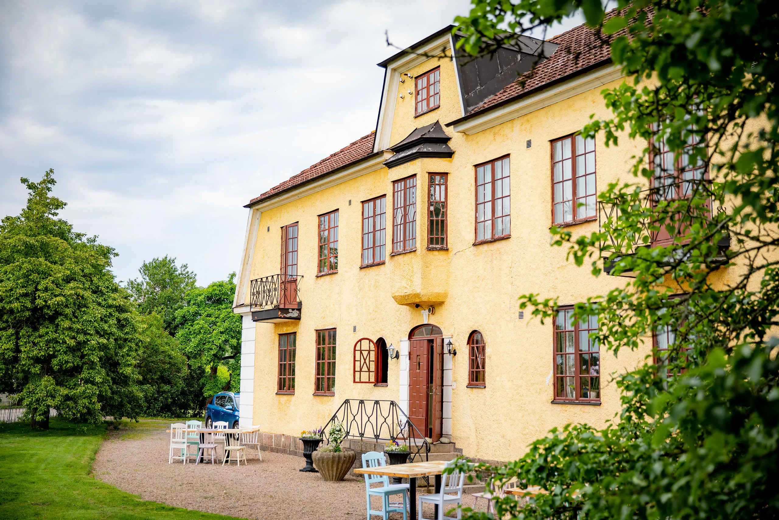 Gult stenhus med trämöbler utanför.