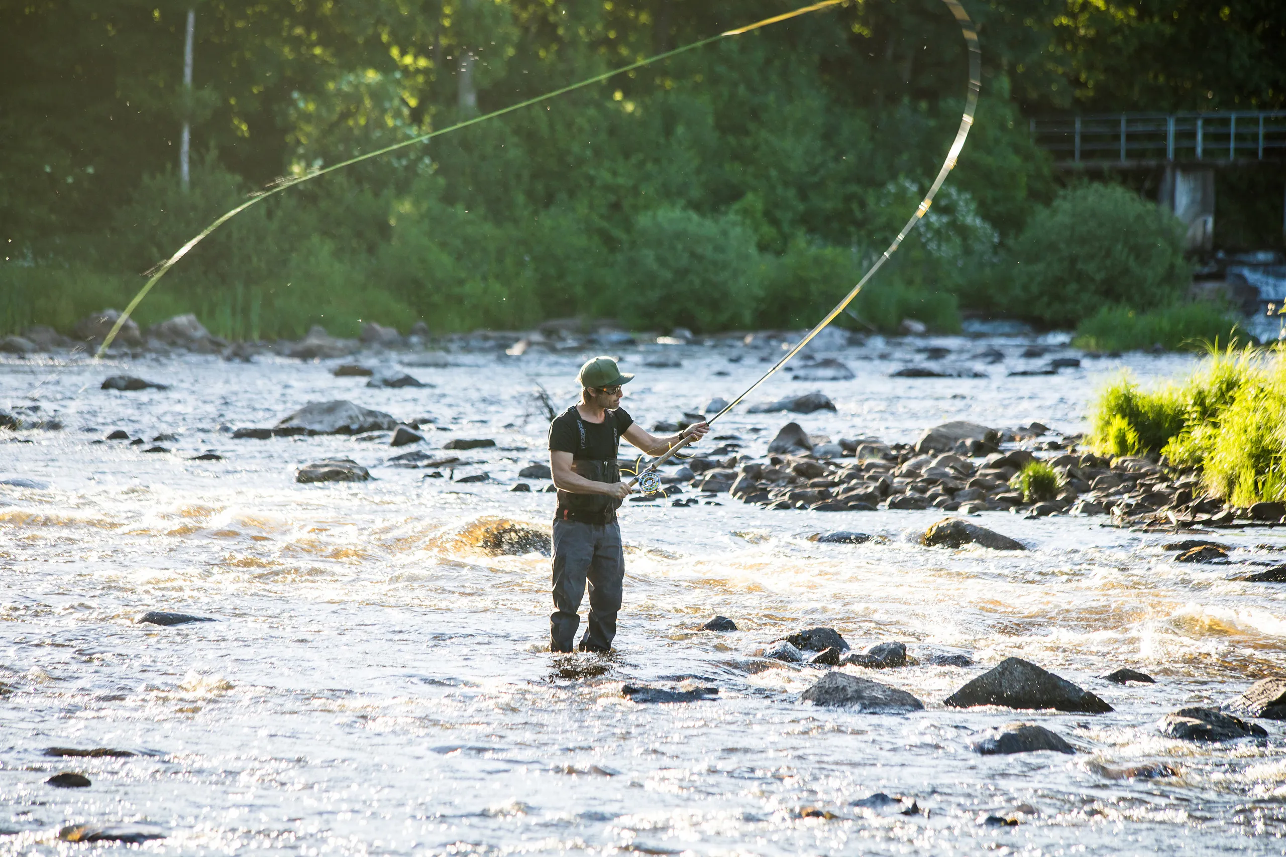 Fiskare i vatten med stenig botten