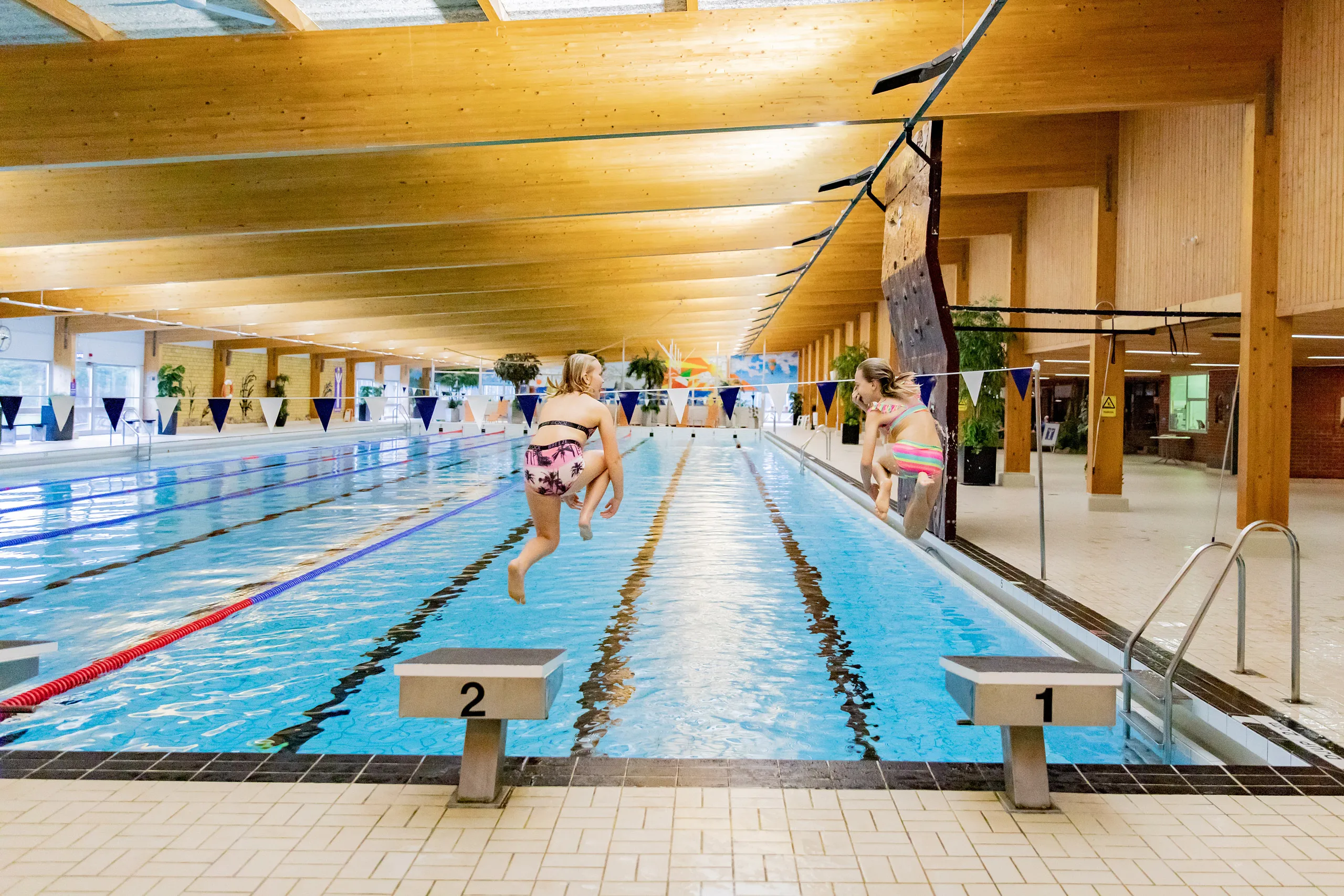 Två flickor som hoppar i bassängen på Klitterbadet