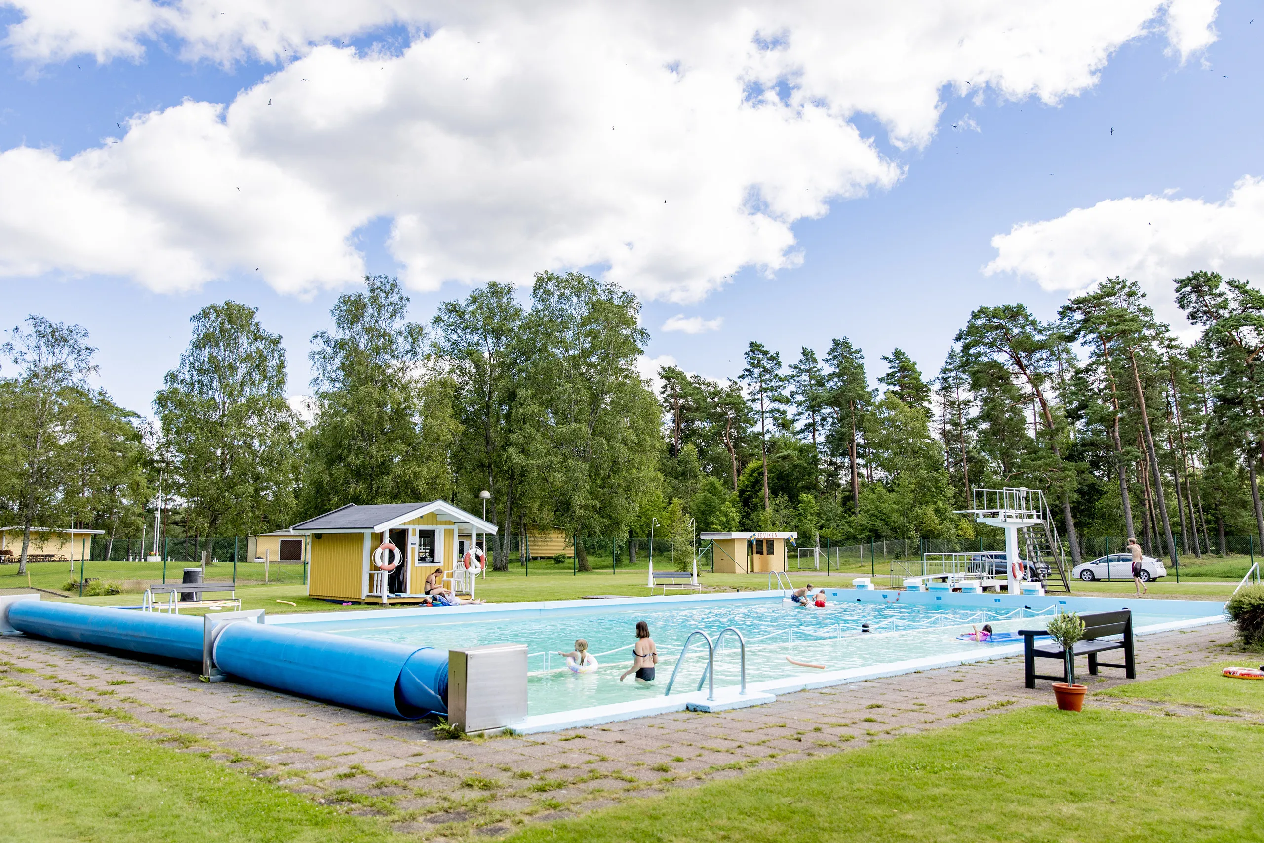 Utomhusbadanläggning med personer i poolen