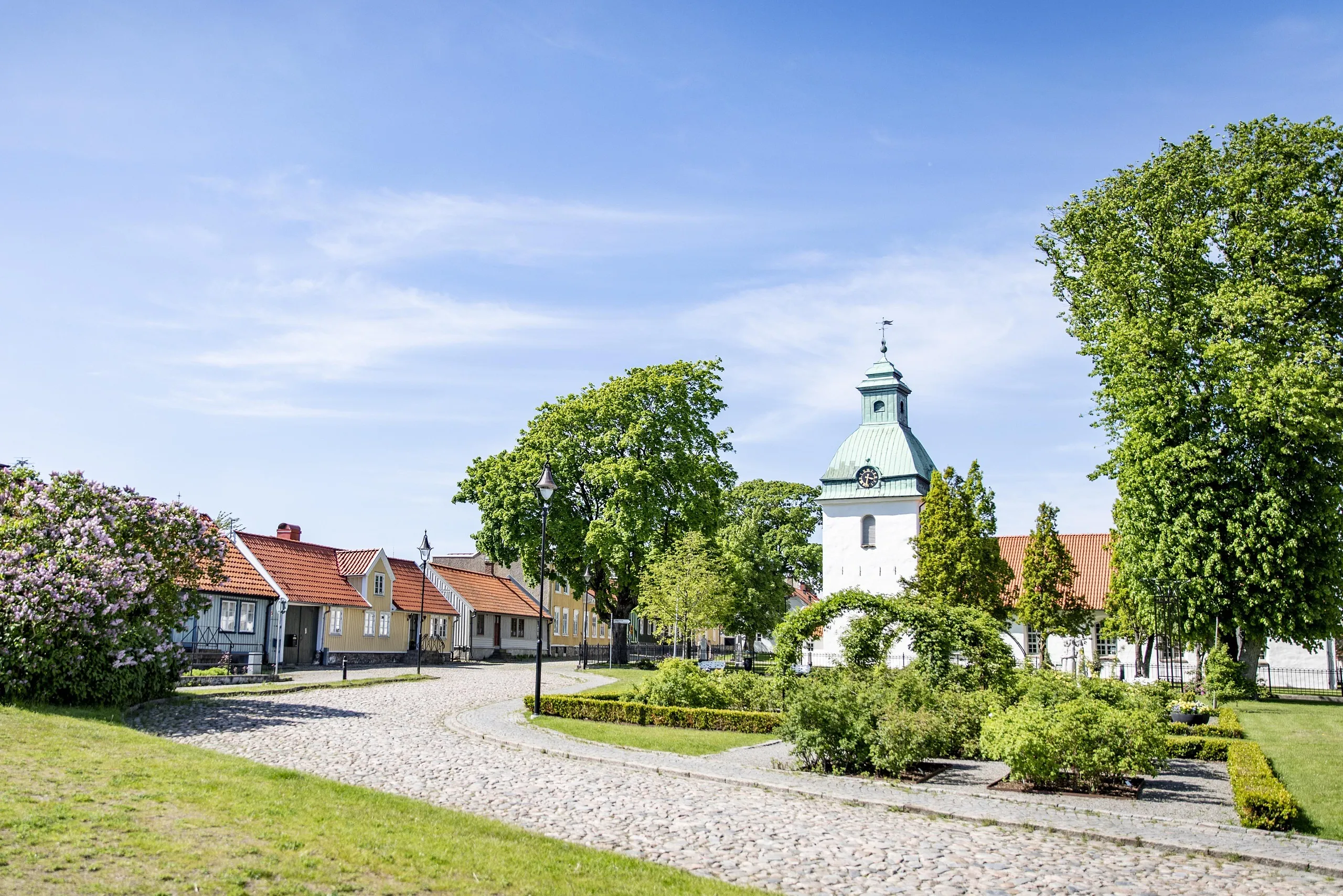 Gammal stadsdel med låga trähus, en vit kyrka och en grönskande park.