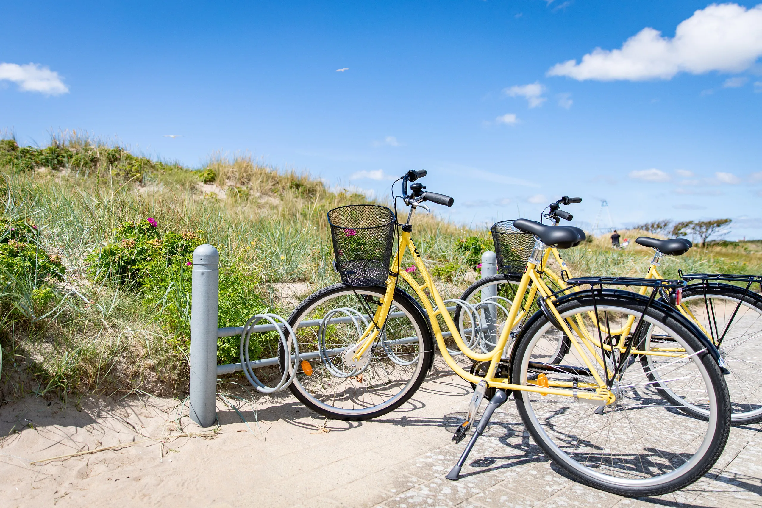 Två gula cyklar i ett cykelställ vid stranden
