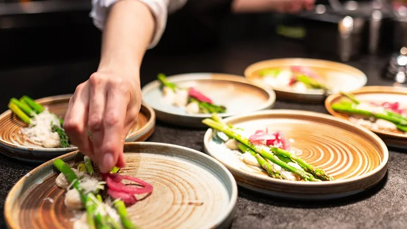 Hand som lägger upp mat på tallrikar.