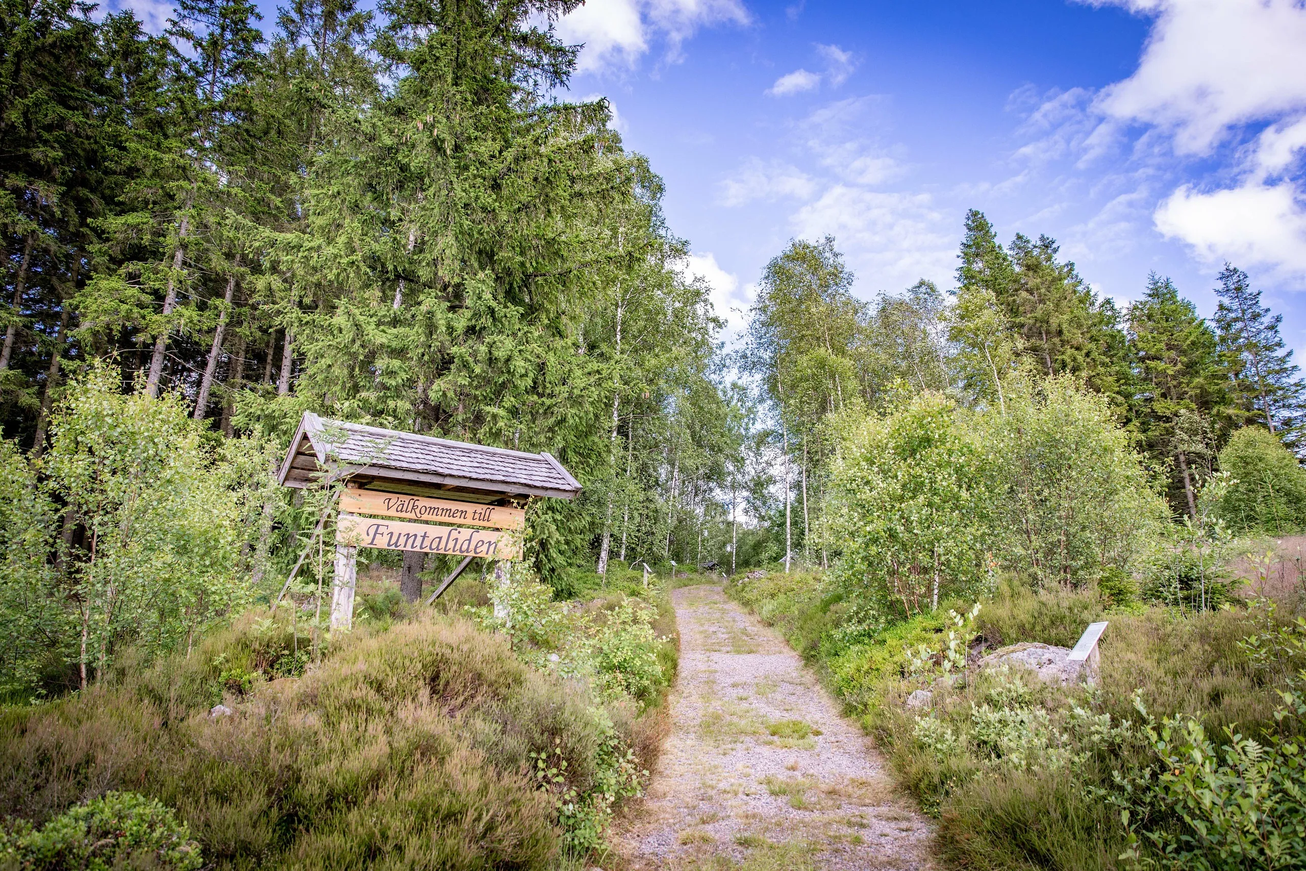 Stig i skog med en informationsskylt.