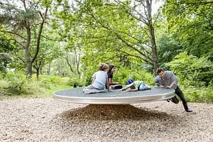 man sätter fart på snurrskiva med barn