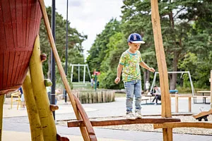 pojke går balansgång på lekplats