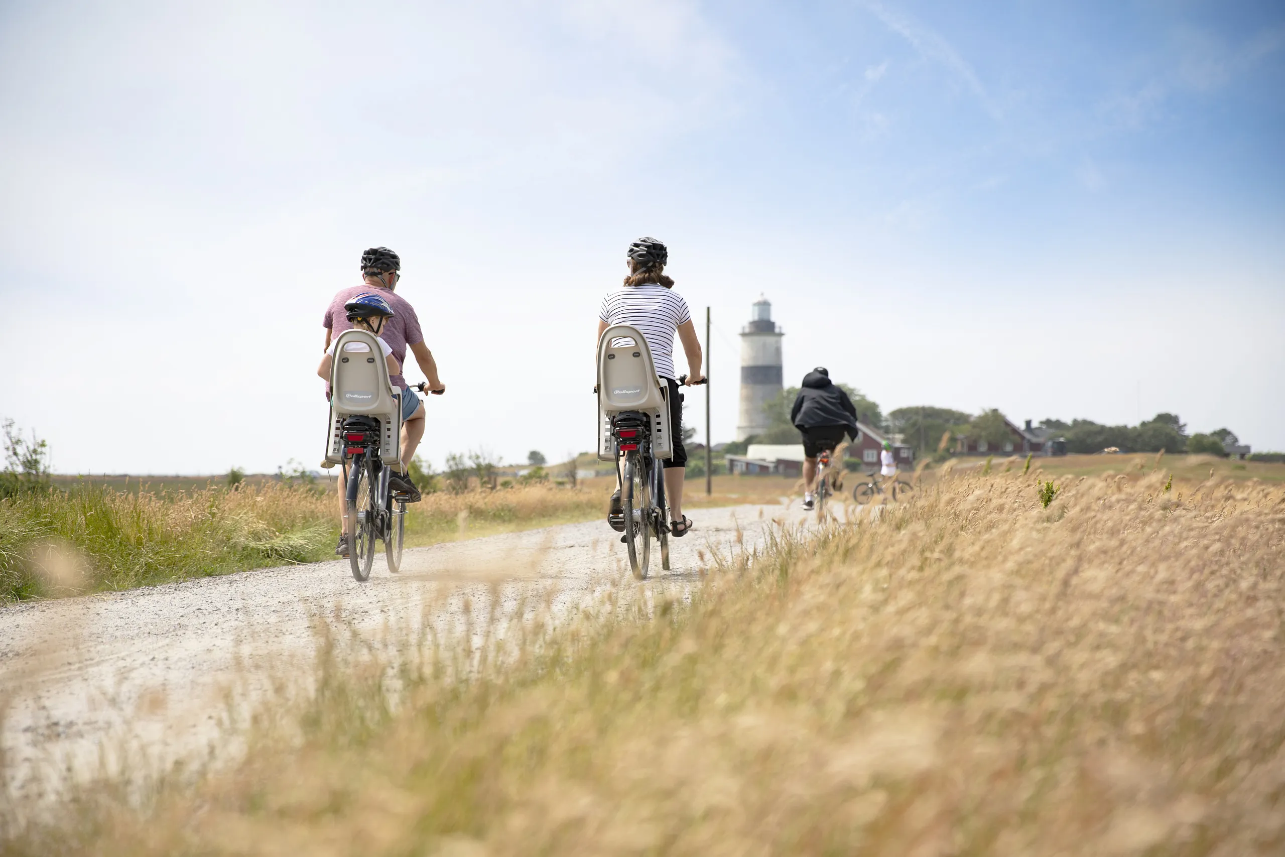 familj som cyklar vid fält och fyr