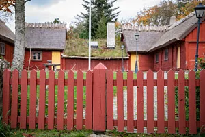 rött staket framför hallandslänga med vasstak
