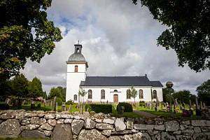 Kyrka framför molnig himmel inramad av grönska