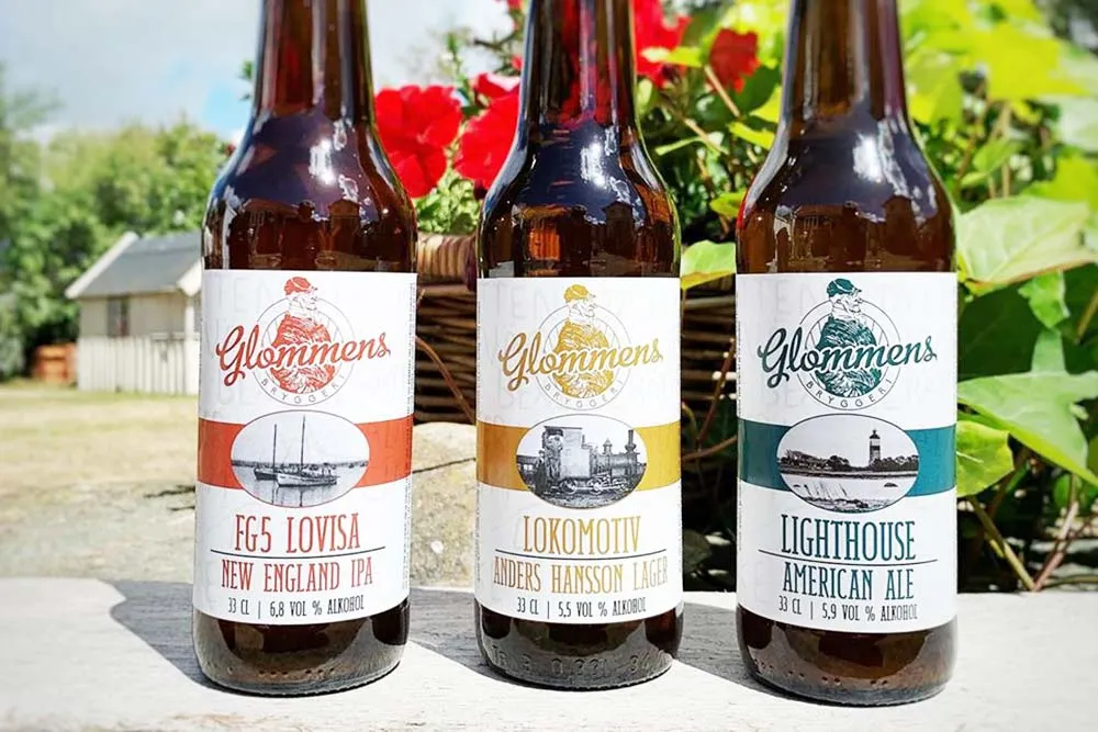 tre ölflaskor på rad framrör grönska