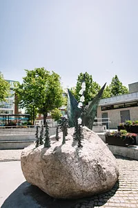 sten med bronsskulptur föreställande blommor