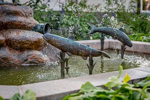 konstverk av hoppande laxar i koppar i fontän