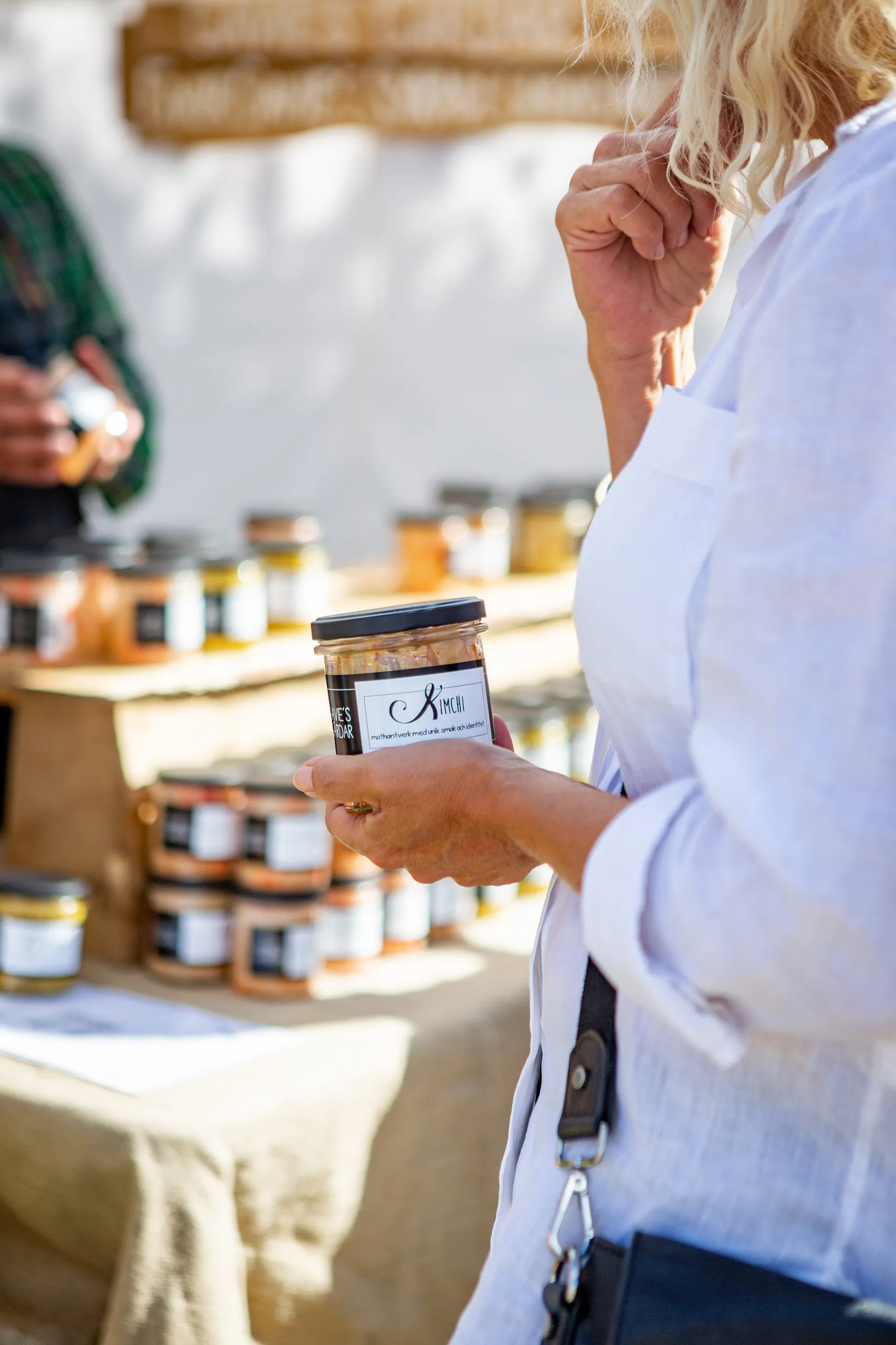 person håller i burk med kimchi framför marknadsstånd