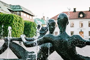 fontänstaty framför stort vitt hus och välklippta träd