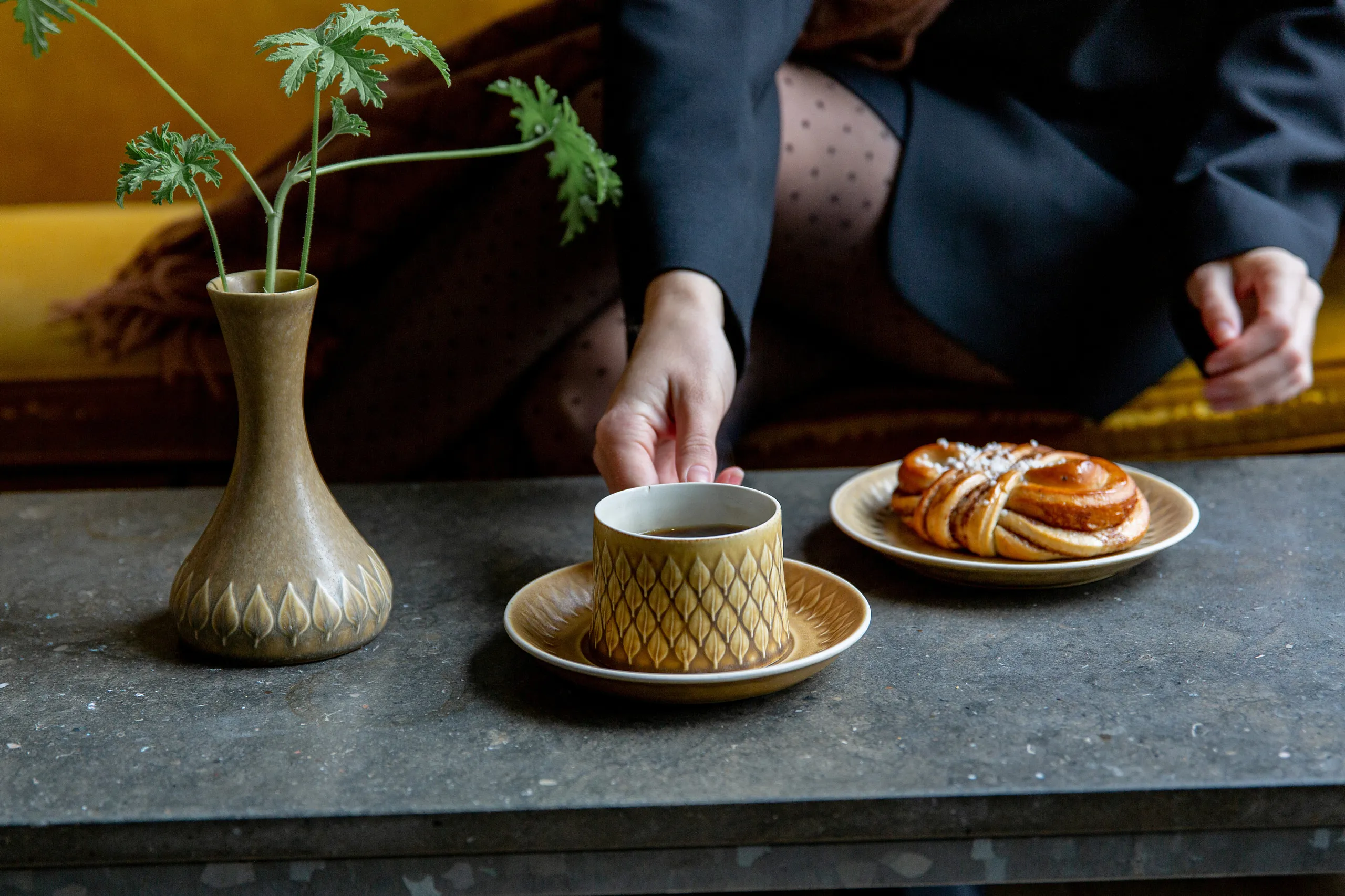Fika med gul kopp, kanelbulle och gul soffa