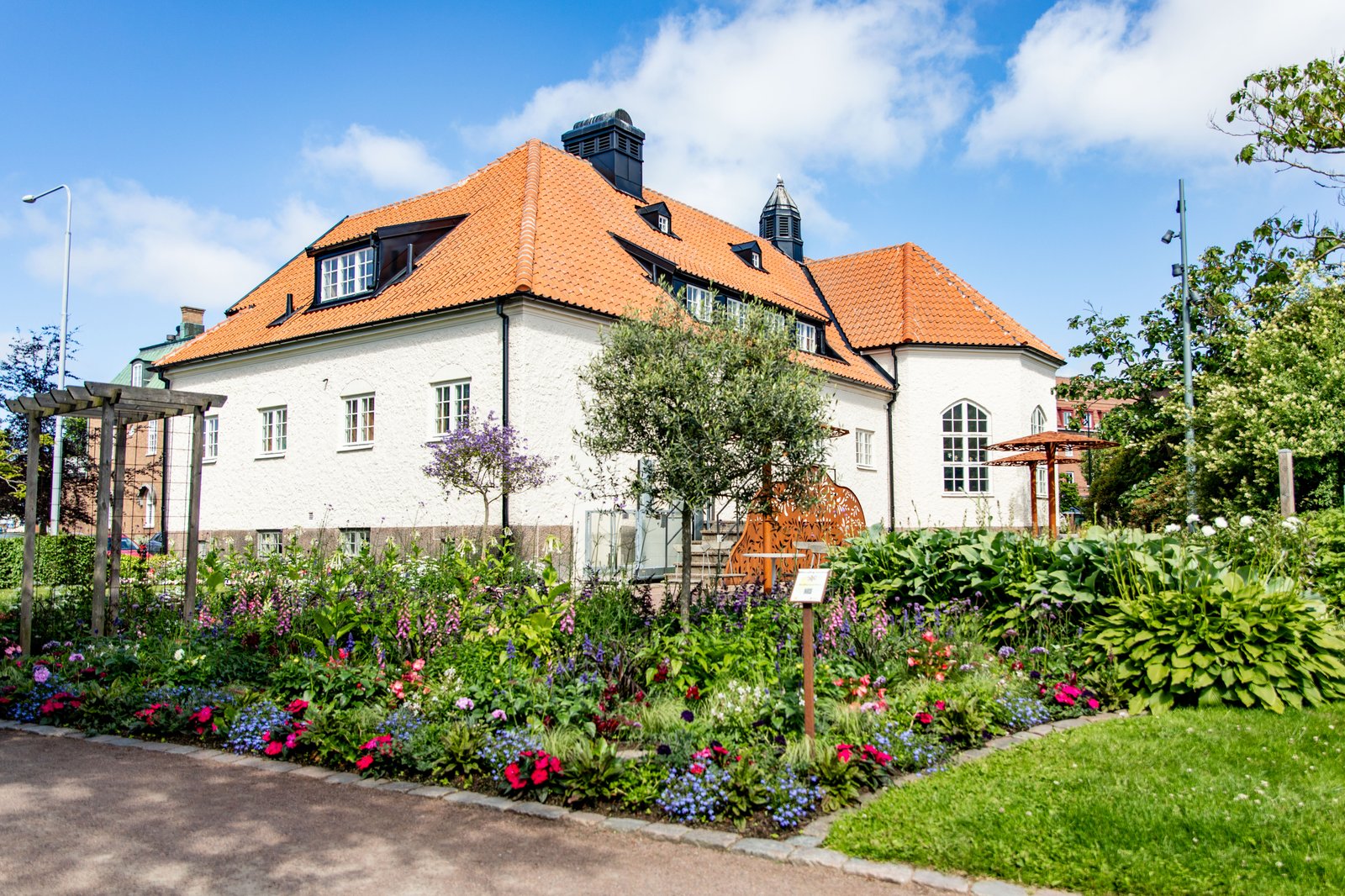 Blomsterrabatter framför ett vitt hus