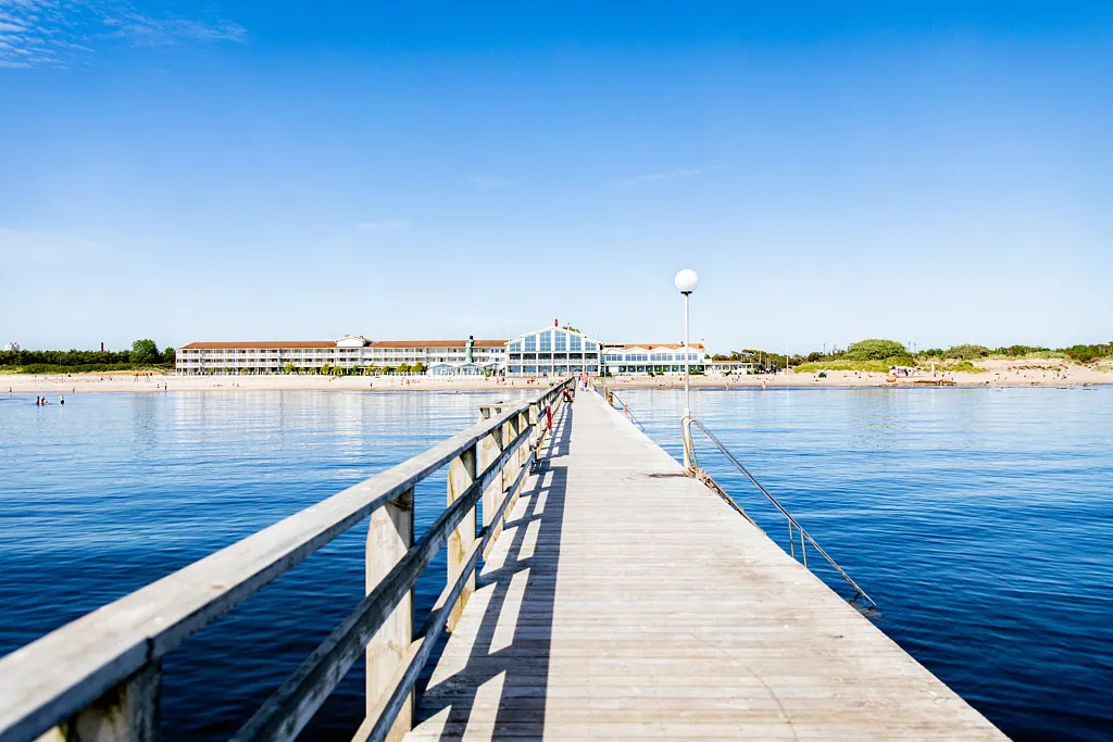 Bild från brygga och in mot stranden, där ligger ett stort vitt hotell.