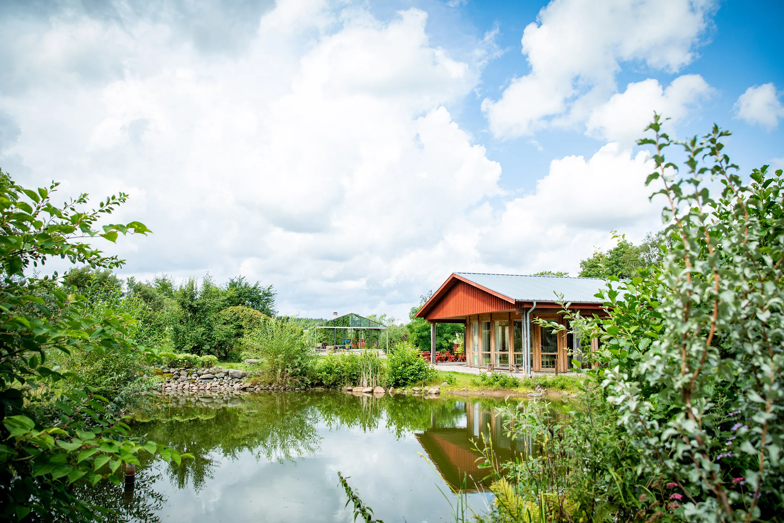 rött hus i natur vid liten damm