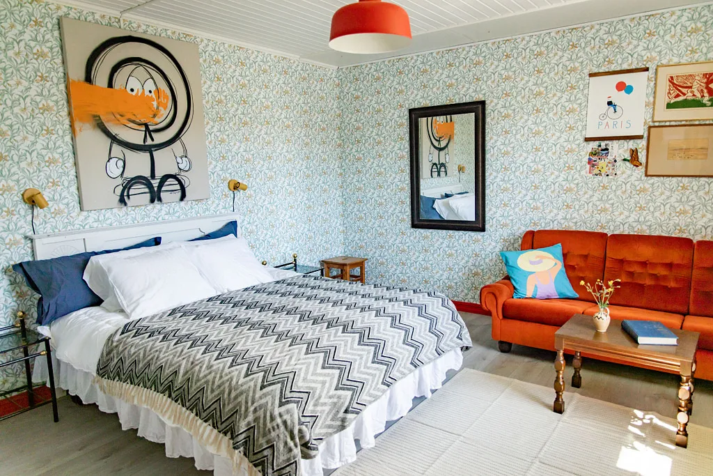 Sovrum med dubbelsäng och röd soffa.