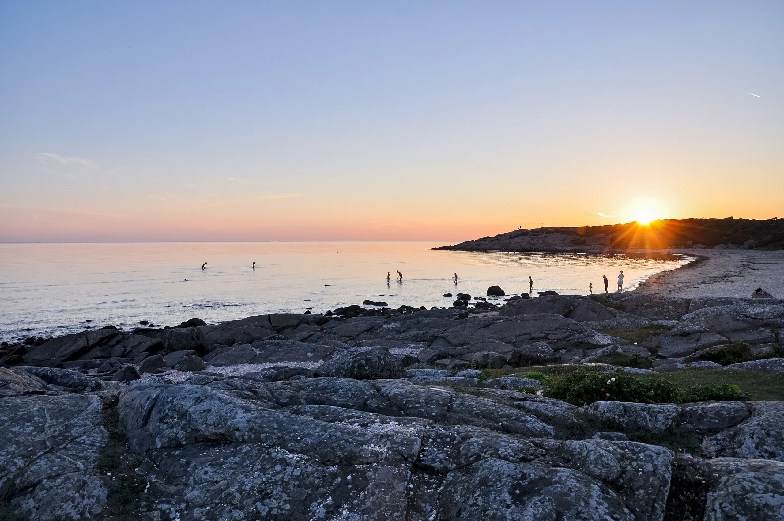 Solnedgång över strand och klippor.