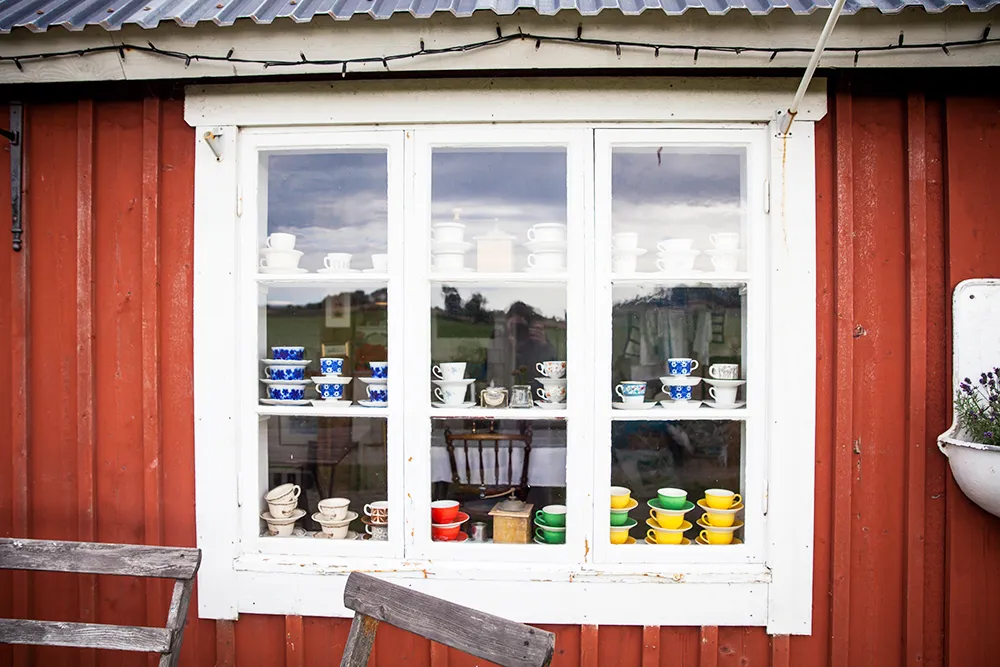 Koppar på hyllor syns bakom ett fönster.