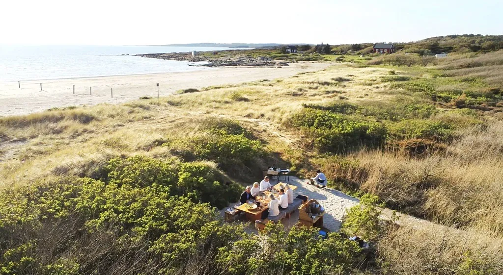 bild tagen uppifrån på sällskap som äter vid ett bord i sanddynerna nära havet