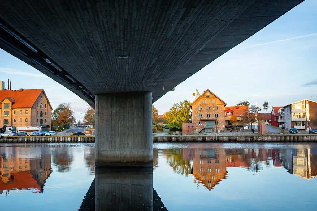 äldre korsvirkesbyggnad bredvid bro speglas i vatten