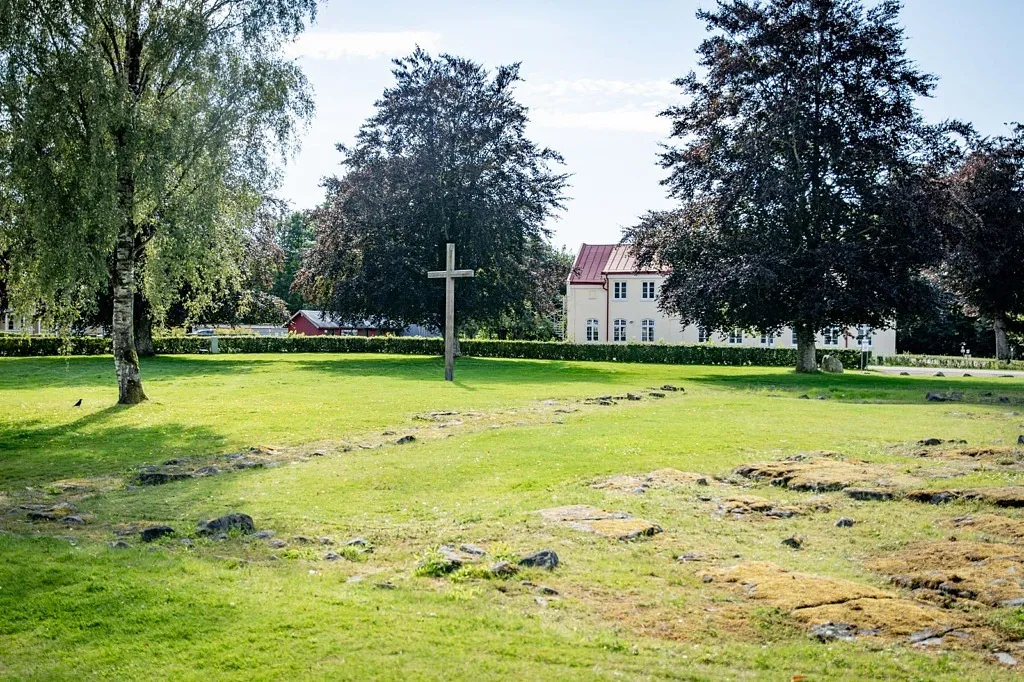 En gammal kyrkoruin som skönjas i gräsmattan.