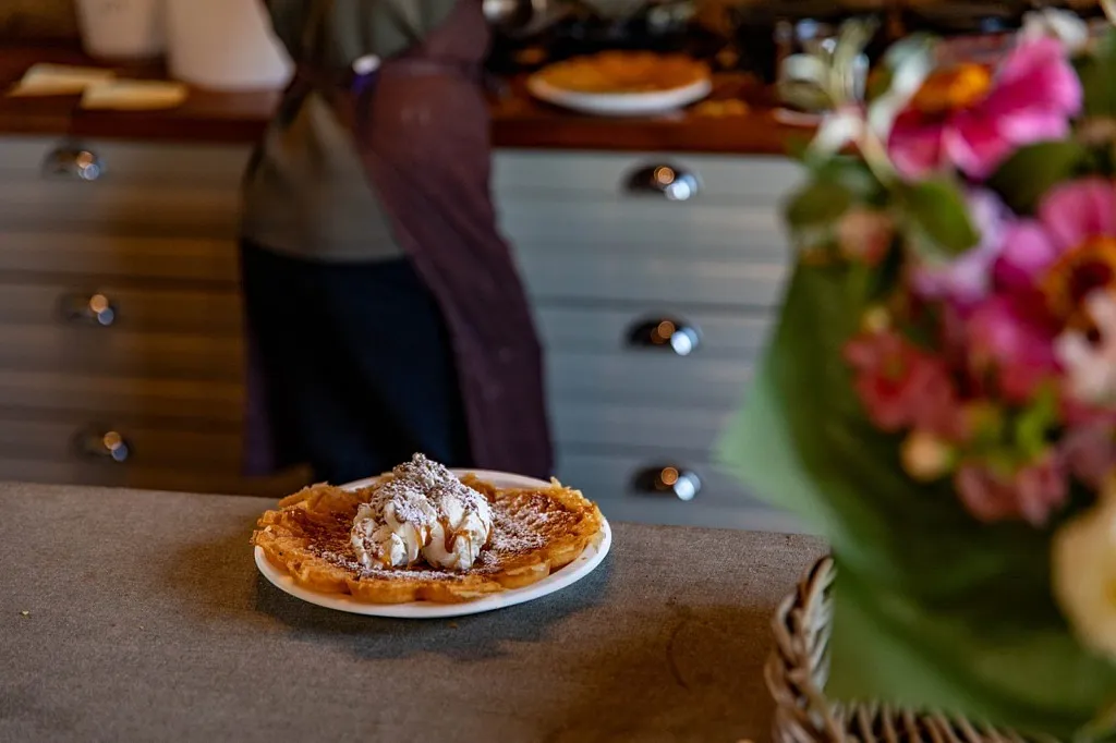En våffla med glass och sirap, i förgrunden står en blombukett.