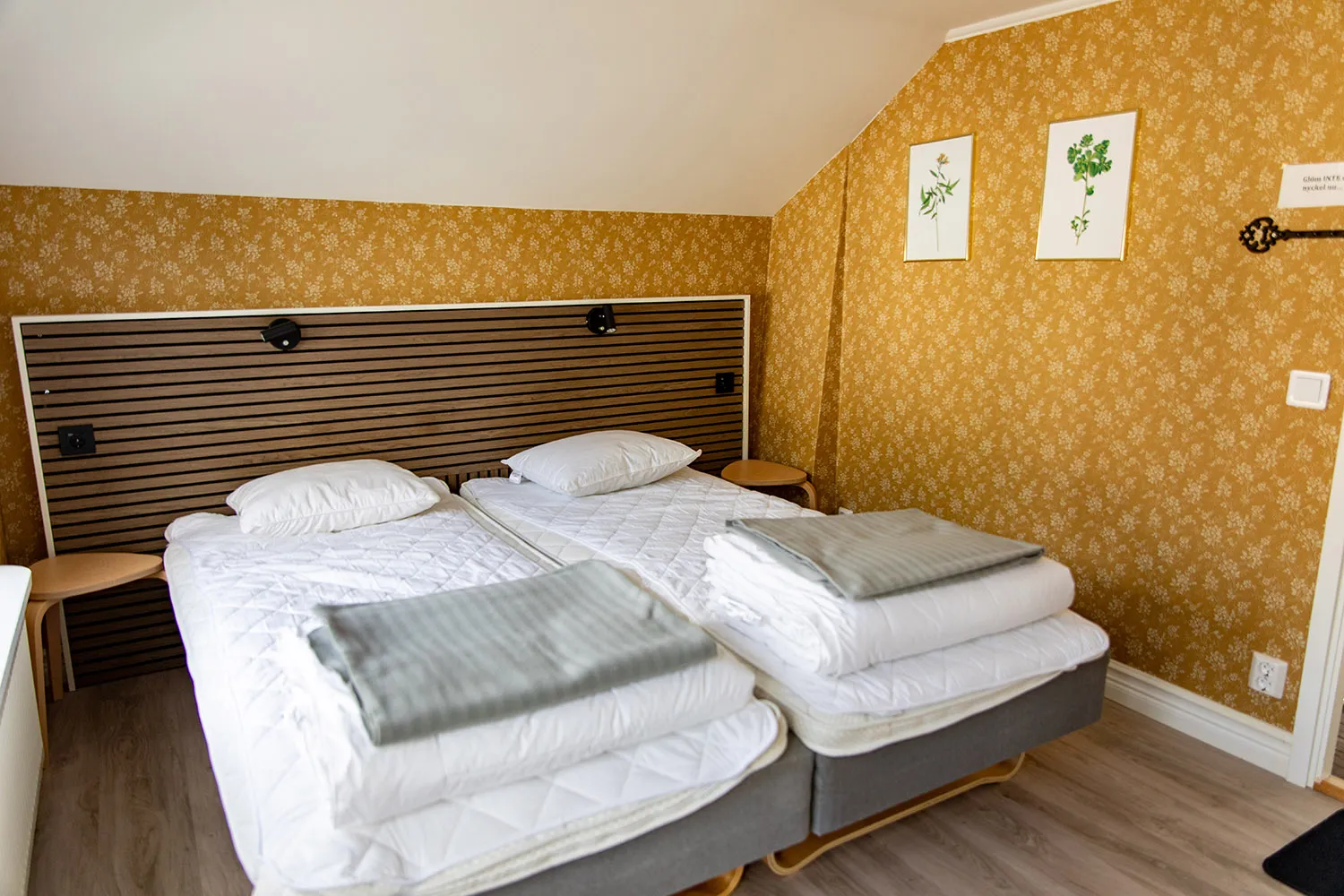 Ett dubbelrum på Hagaberget med gula tapeter och två sängar.