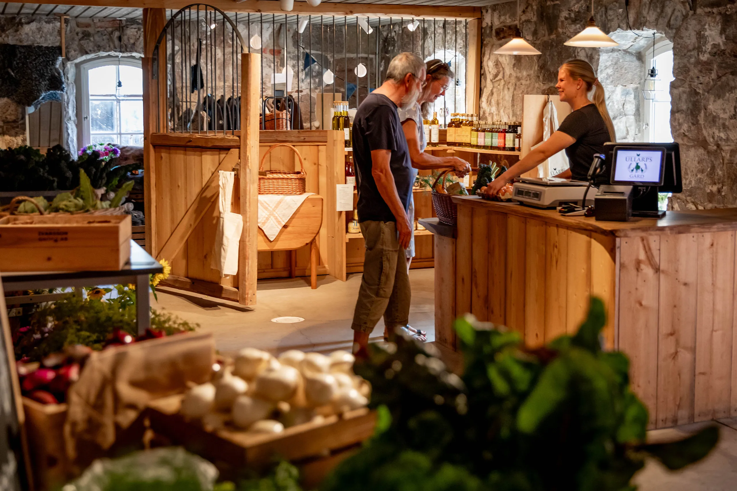 Ett par som betalar vid kassadisken i en gårdsbutik med grönsaker.