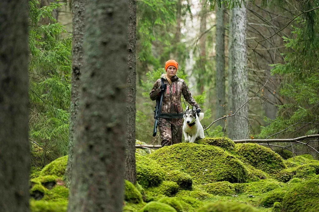 en jägare med hund går i skogen