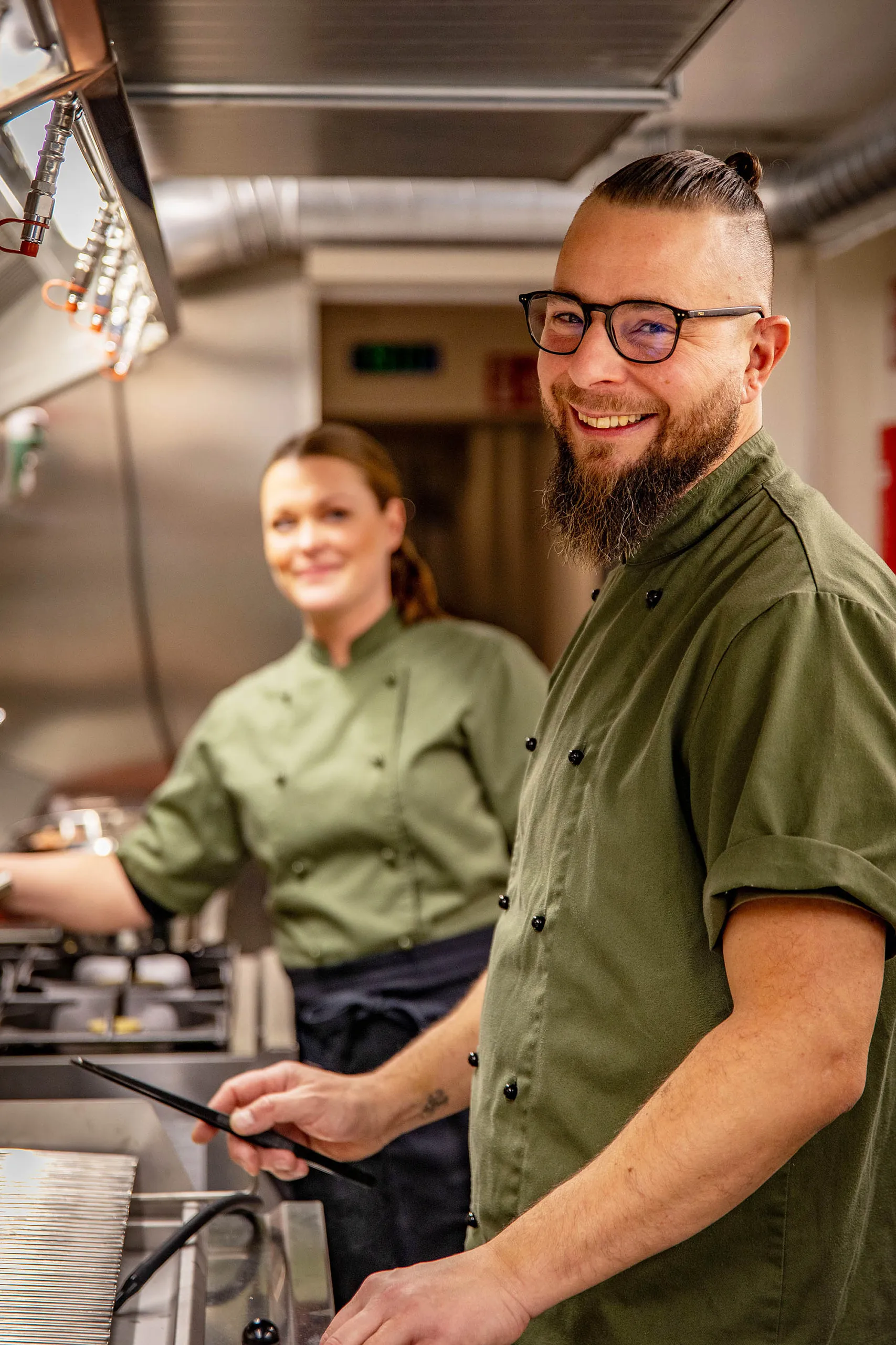 Två glada kockar i ett restaurangkök.