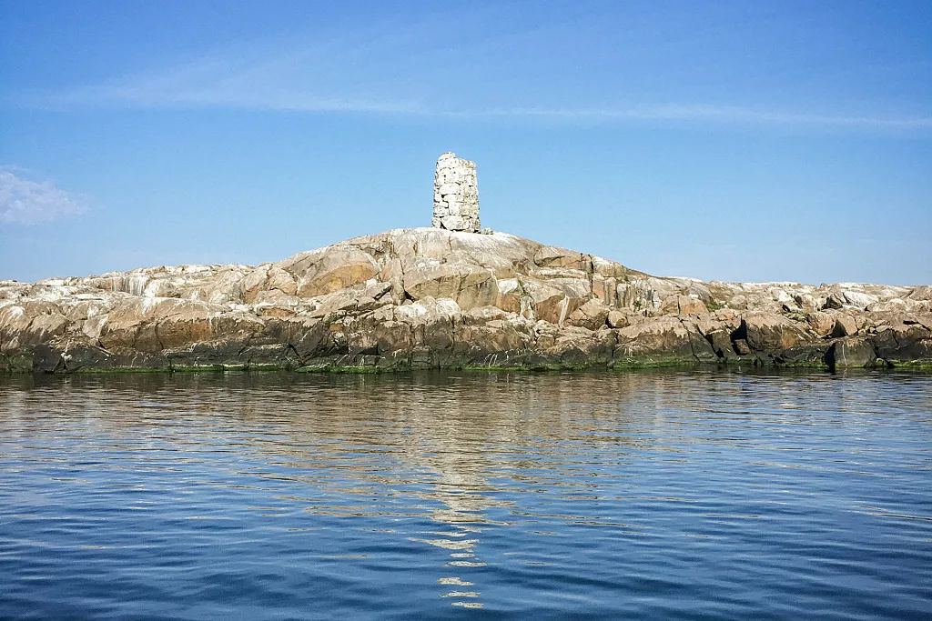 En stenig ö i havet med en vit kummel på toppen.