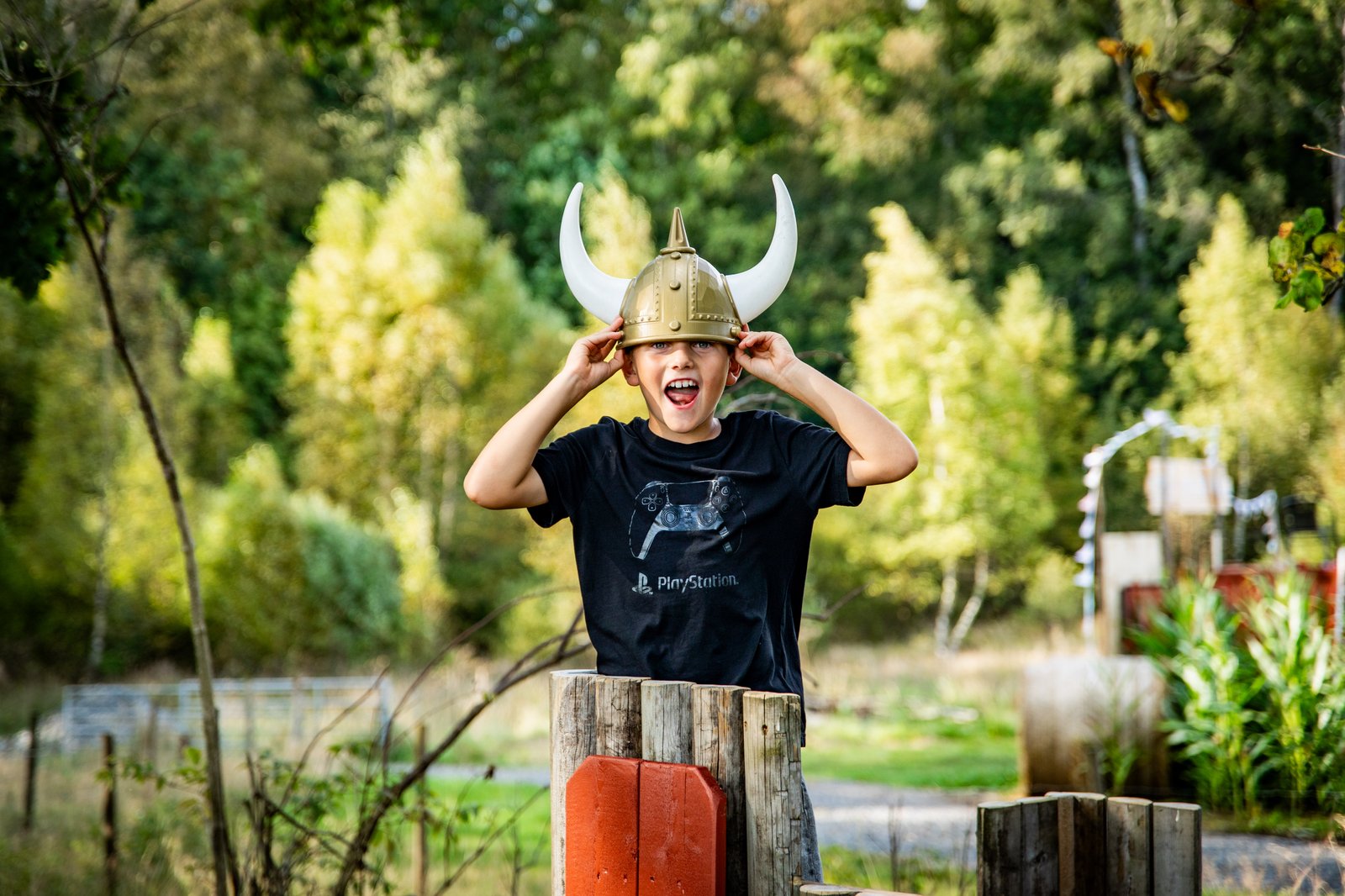 Pojke som står i en träkoja med en vikingahjälm på huvudet.