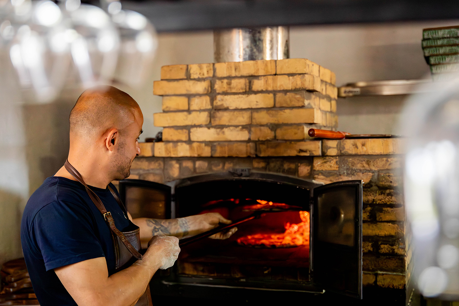 Man som skjutas in en pizza. en vedeldad ugn.