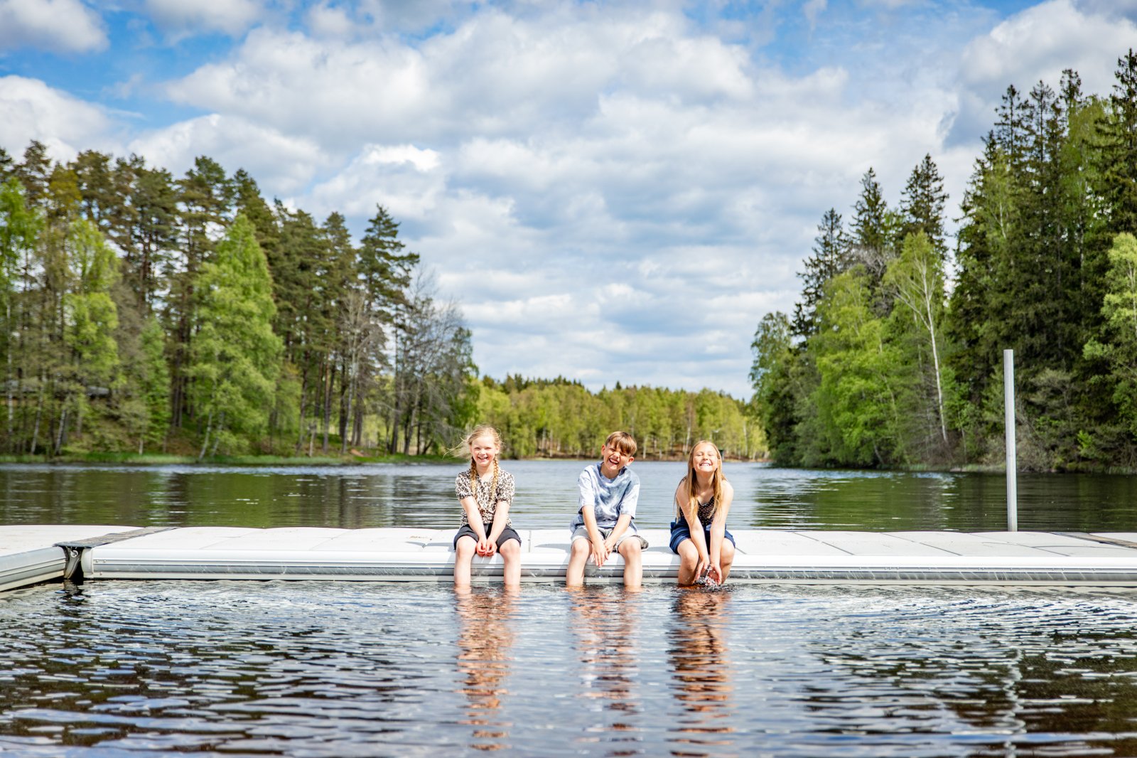 tre barn sitter på bryggan i eseredssjön