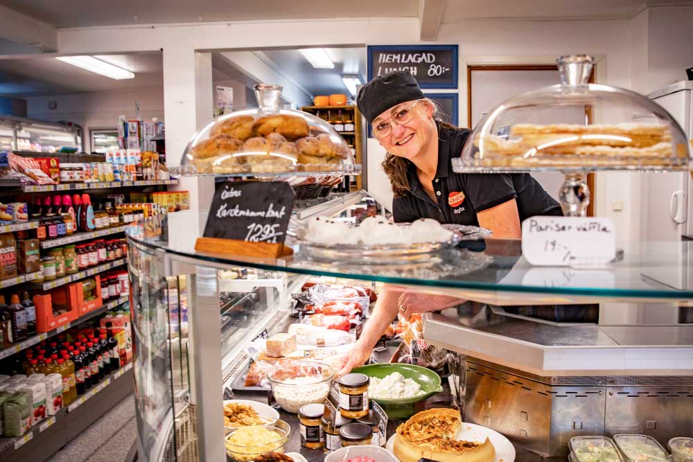 en kvinna står bakom en delikatessdisk i en butik